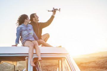 Happy,Couple,Using,A,Drone,Sitting,On,Top,Of,Vintage