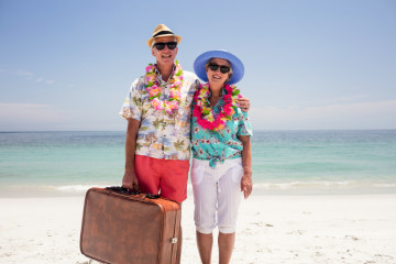 Happy,Senior,Couple,Wearing,A,Garland,And,Holding,Suitcase,On