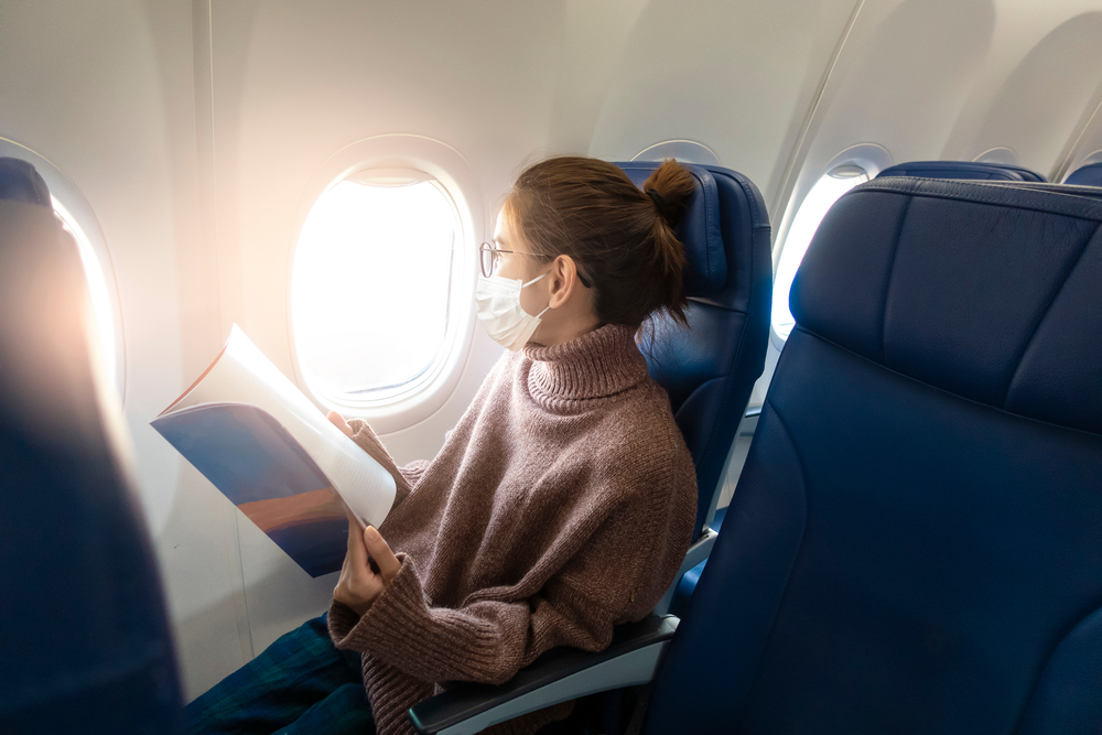 A,Young,Woman,Wearing,Face,Mask,Is,Traveling,On,Airplane