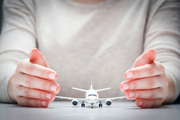 Airplane,Model,Surrounded,By,Hands,In,Gesture,Of,Protection.,Concept