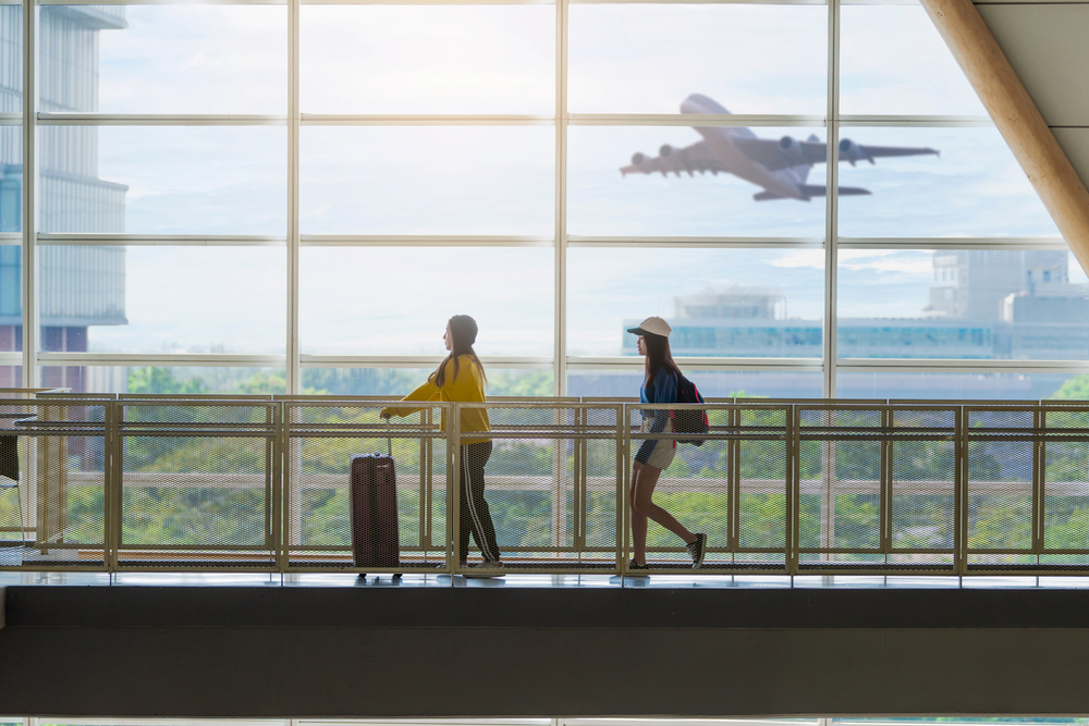 Two,Happy,Asian,Girls,Traveling,Abroad,Together,,Carrying,Suitcase,Luggage