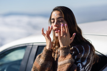Young,Woman,Applying,Sunscreen,On,Her,Face,In,Snow,Landscape