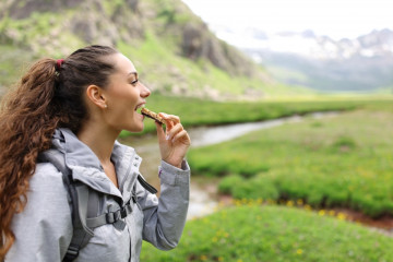 Profile,Of,A,Hiker,Eating,Cereal,Bar,In,A,Valley