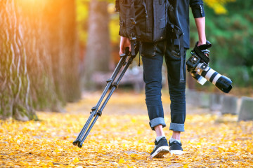 Professional,Photographer,With,Camera,And,Tripod,In,Autumn.