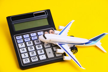 Airplane,Model,And,Calculator,Yellow,Background.concept,Of,Costs,Or,Expenses
