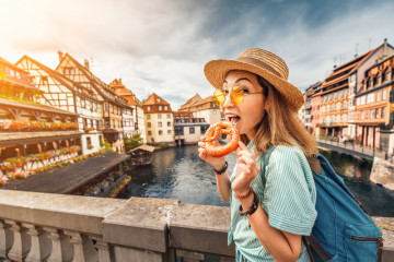 Happy,Asian,Girl,Tourist,Eating,Delicious,Pretzel,While,Travelling,In