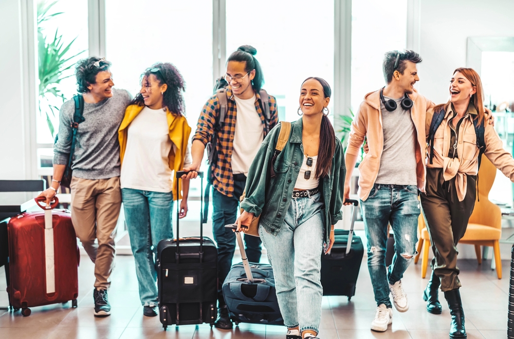 Young,Group,Of,Tourists,With,Suitcases,Arriving,At,Youth,Hostel