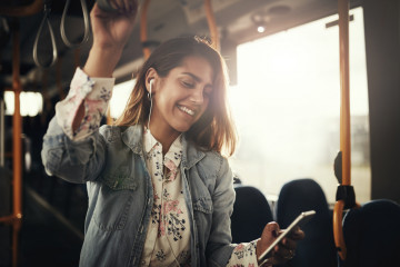 Young,Woman,Smiling,While,Standing,By,Herself,On,A,Bus