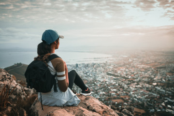 Young,Woman,With,Backpack,Sitting,On,Top,Of,High,Mountain