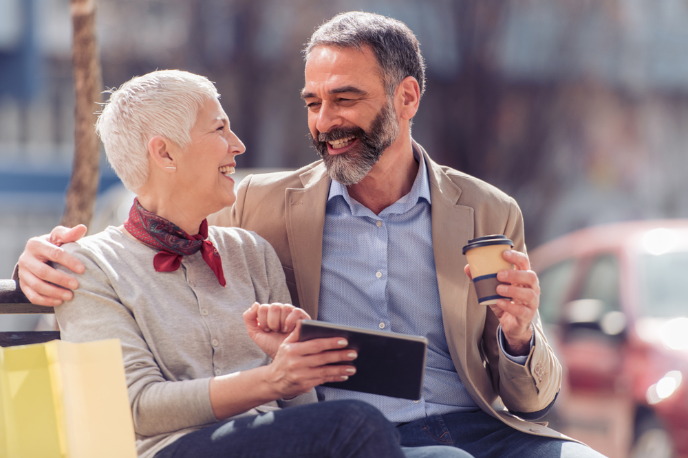 Mature,Couple,Relaxing,After,Shopping,using,Tablet.