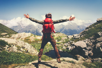 Traveler,Man,With,Backpack,Jumping,Hands,Raised,Mountains,Landscape,On