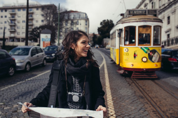 Female,Traveler,Holding,And,Reading,Tourist,Map,,waiting,The,Tram,using
