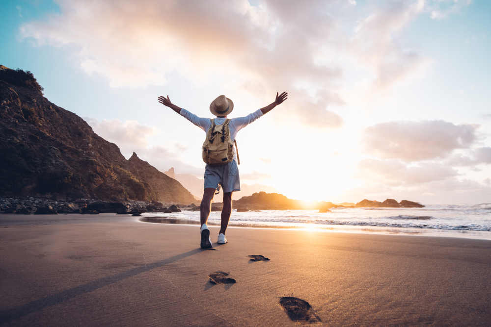 Young,Man,Arms,Outstretched,By,The,Sea,At,Sunrise,Enjoying