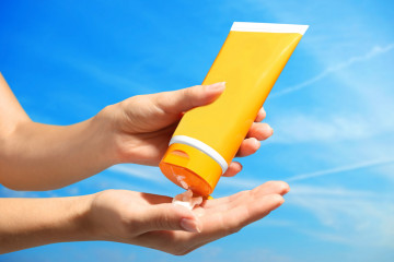 Female,Hands,With,Sun,Protection,Cream,On,Sky,Background.,Skin