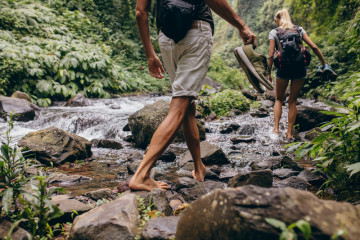 Low,Section,Shot,Of,Man,And,Woman,Crossing,The,Stream