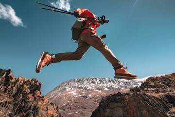 Man,Hiker,With,Hiking,Poles,And,Backpack,Jumps,Over,The