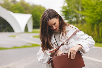 Elegant,Young,Woman,Looking,In,Her,Brown,Bag,Her,Phone