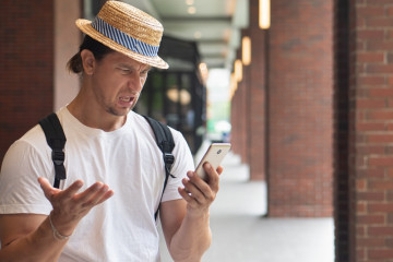 Angry,Upset,Man,Traveler,Using,Smartphone,,Experiencing,Online,Scam,,Internet